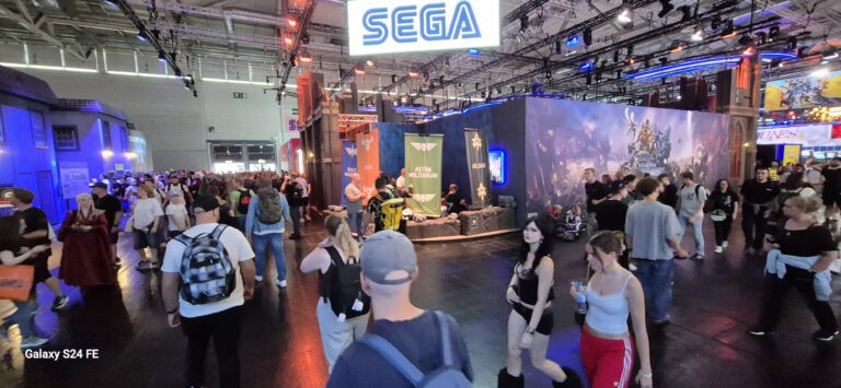 Blick auf einen großflächig gestalteten Sega-Messestand mit Besuchern.