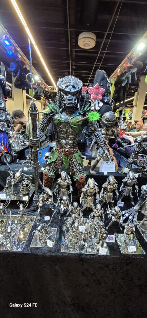 Vitrine mit kleinen Figuren und Sammlerstücken an einem Gamescom-Stand.