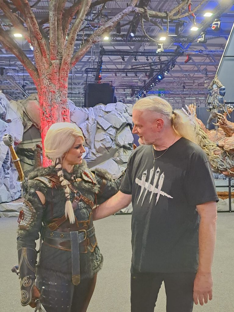 Ciri-Cosplayerin im Gespräch mit einem Besucher vor dem Witcher-Stand.