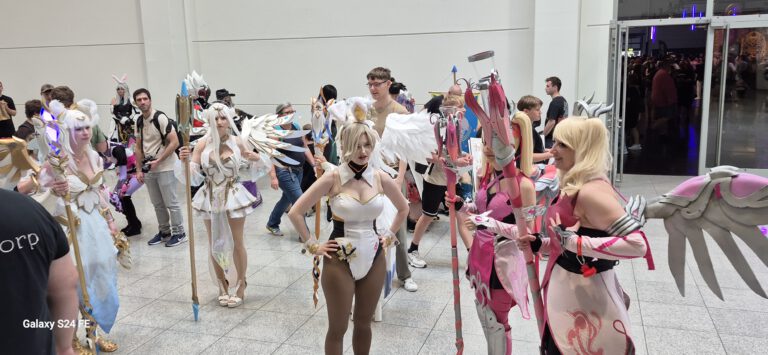 Mehrere Besucher in detailreichen rosa-weißen Fantasy-Cosplays mit Flügeln.